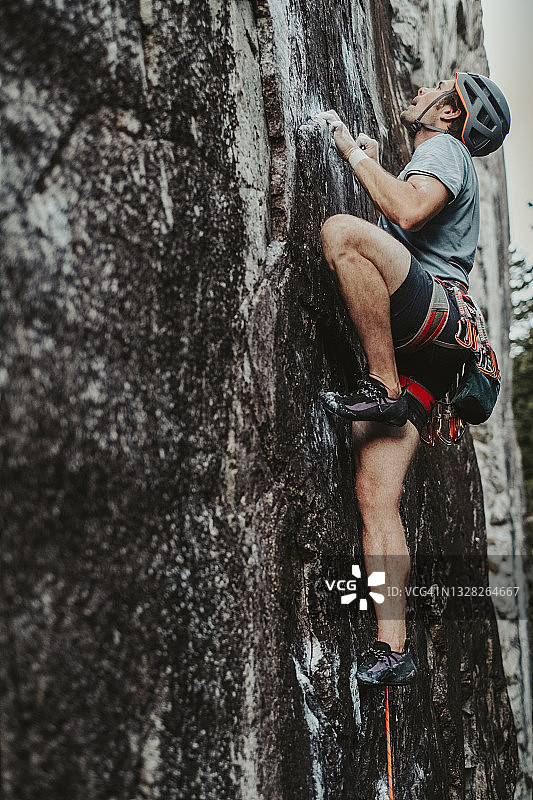 攀岩者专注于攀登具有小手和脚支撑的垂直悬崖图片素材