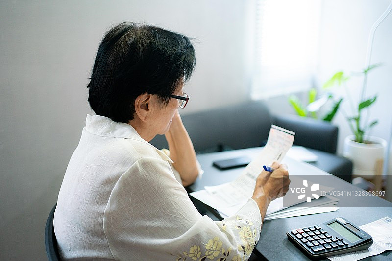 亚洲老年妇女计算每月开支并核对收据准备付款图片素材