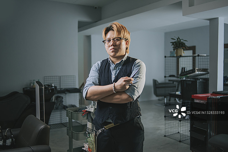 亚洲华人发型师在理发店面带微笑自信地看着镜头图片素材
