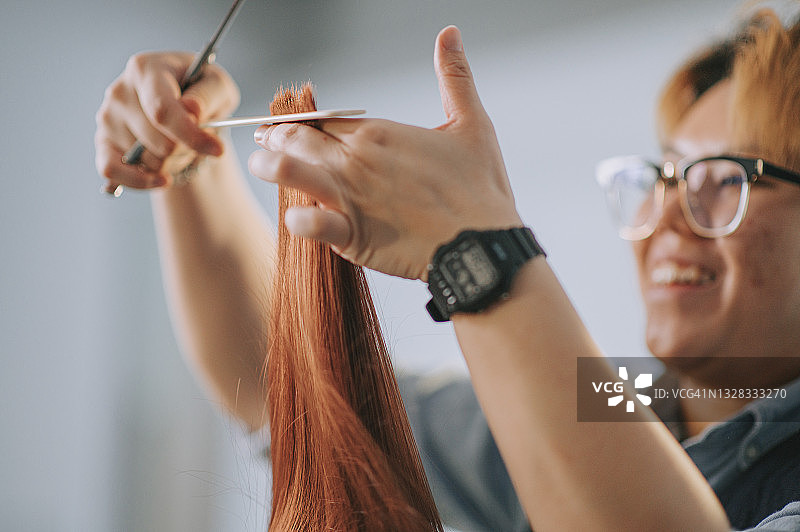 亚洲女发型师在美发沙龙为顾客剪发特写图片素材