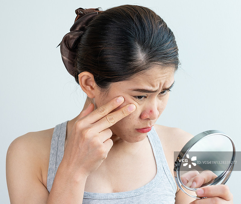 年轻的亚洲女人担心鼻子上的痤疮问题图片素材