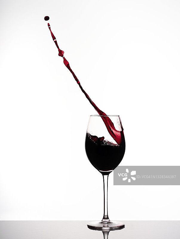 从装满红酒的玻璃杯中飞溅而出，白色背景图片素材
