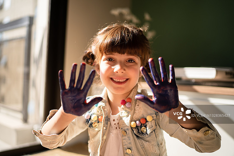 可爱小女孩展示沾满颜料的双手图片素材