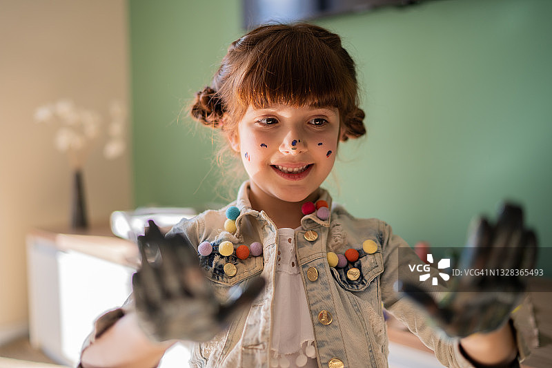 展示沾满油漆的手的可爱女孩图片素材