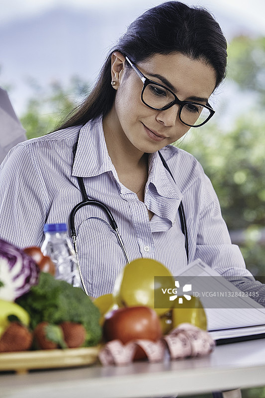 营养饮食概念：西班牙裔年轻营养师在工作场所，带文案空间图片素材