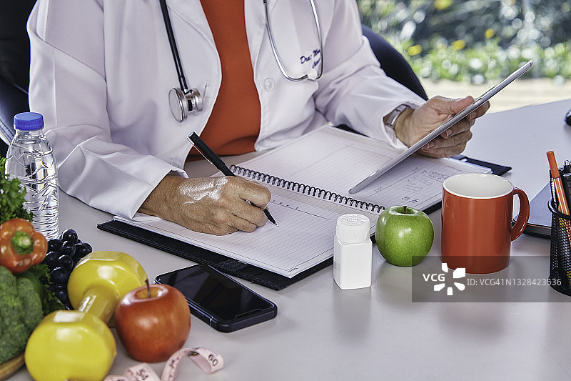 营养饮食概念。营养师坐在办公室里在文书上写作图片素材