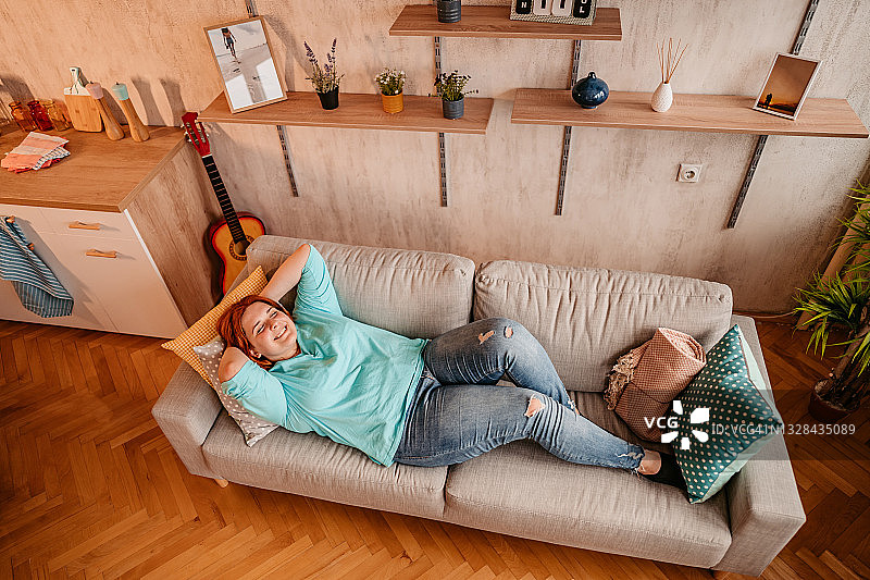 女人在沙发上放松，双手放在脑后图片素材