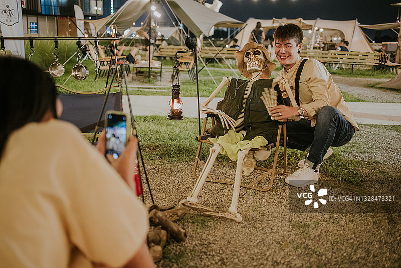 万圣节概念咖啡厅里英俊男子拥抱人类骨骼的照片图片素材