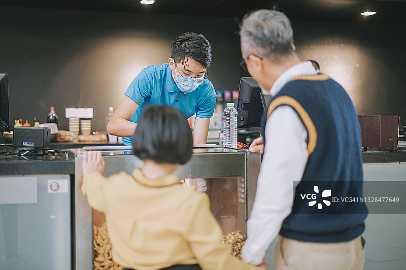 中国祖父和孙女在电影院吧台前点爆米花图片素材