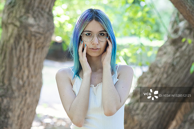 树下戴眼镜的蓝色头发年轻女子图片素材