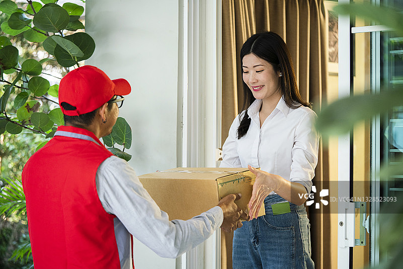 快递员给年轻女子送包裹图片素材