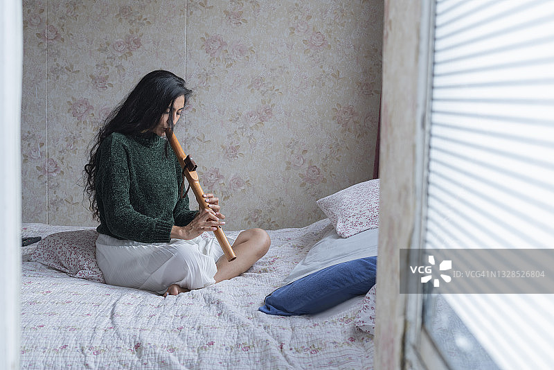 拉丁裔女人在舒适的家中演奏长笛图片素材