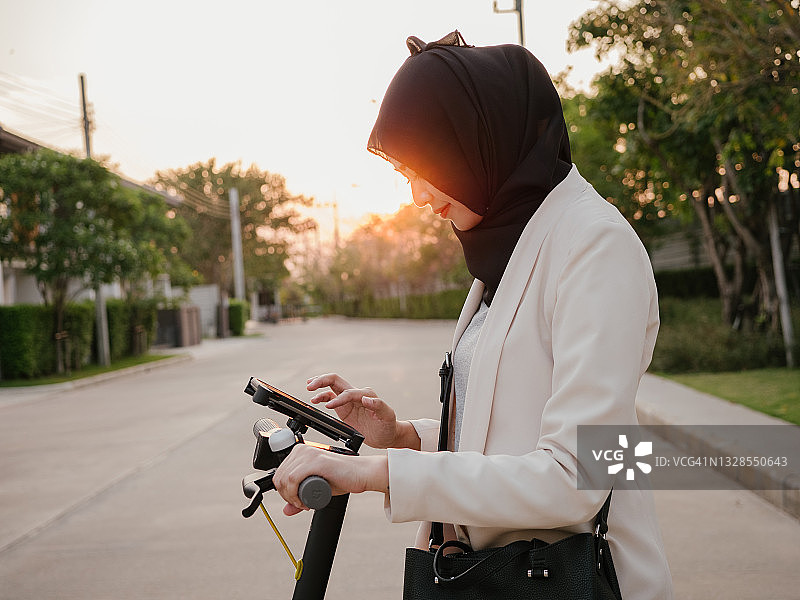 年轻女子骑着电动滑板车在城市通勤。图片素材
