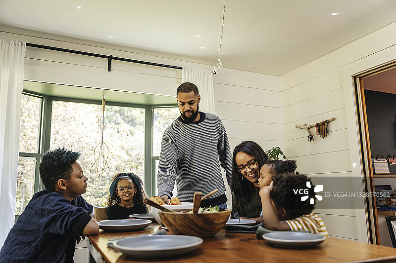 男人在家中餐桌上为家人提供食物图片素材