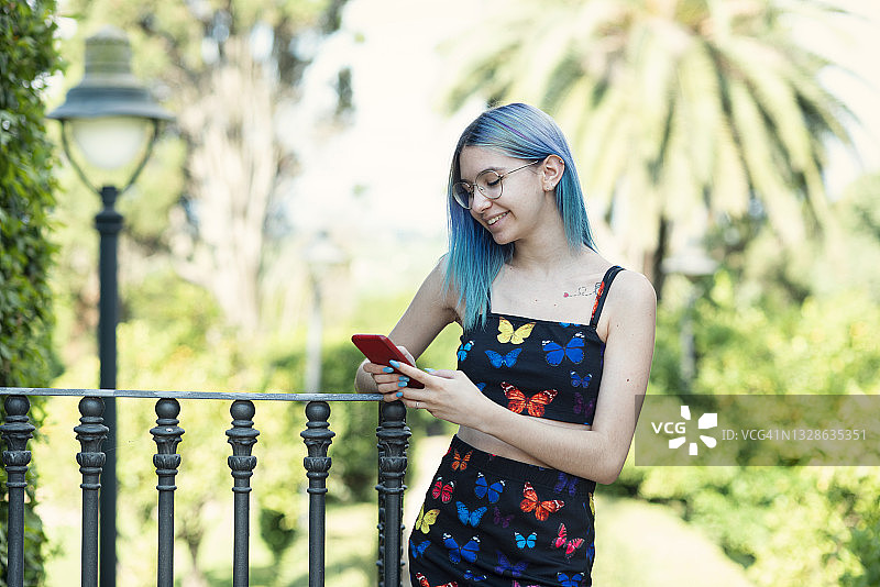 蓝头发的女人在公园使用手机图片素材