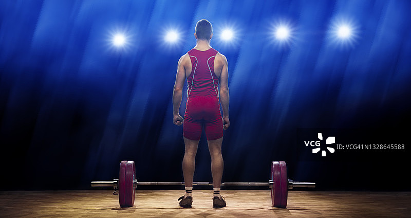 男举重运动员站在杠铃旁边的背影图片素材