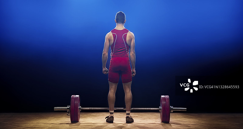 男举重运动员站在杠铃旁边的背影图片素材