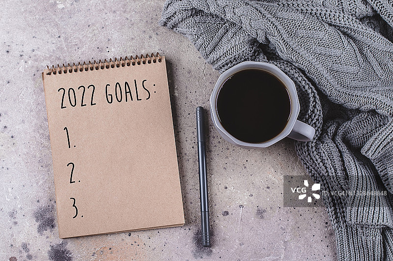 2022新年目标：新年计划的概念，一杯咖啡、舒适的灰色毛衣和带笔的笔记本图片素材