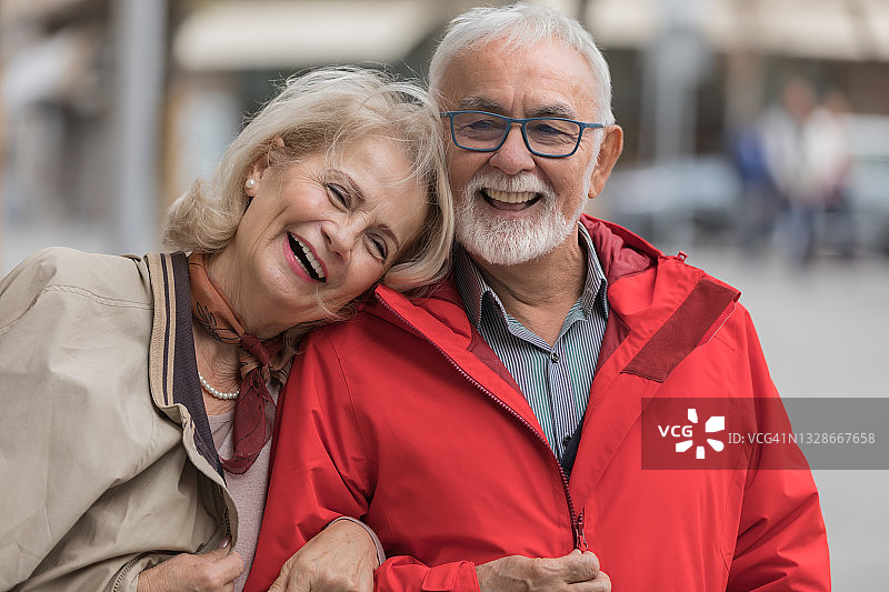 相爱的老年夫妇在城市街区漫步，享受秋日午后时光图片素材