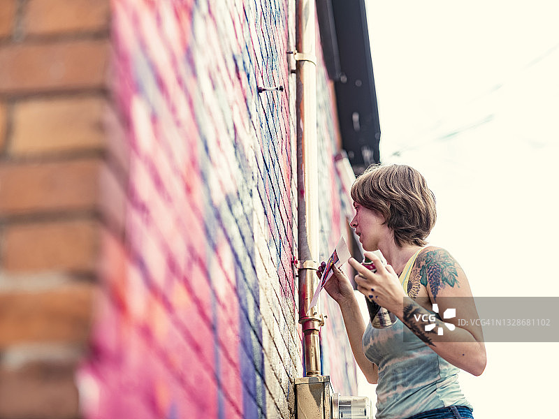 年轻女人在房子上画壁画图片素材