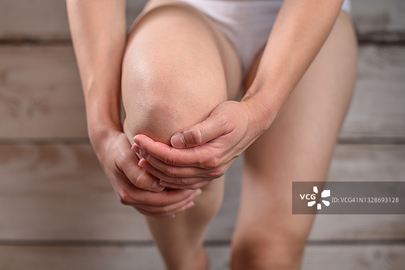 痛苦地捂着膝盖的女人图片素材