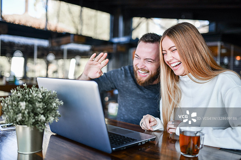 情侣在餐厅用笔记本电脑进行有趣的视频会议，同时品茶图片素材