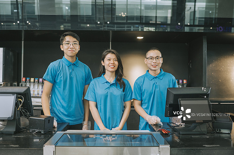 在电影院小吃摊前微笑看向镜头的亚洲快餐店女员工肖像图片素材