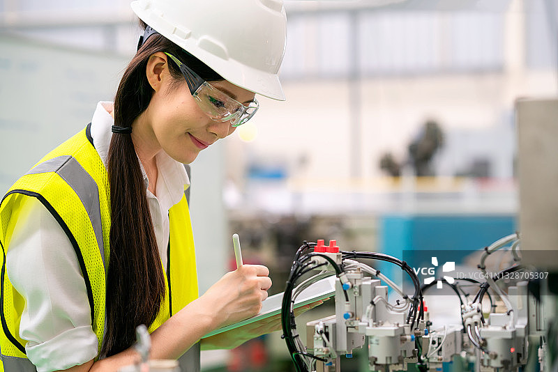在机器人工厂检查自动化机器的工业女工程师图片素材