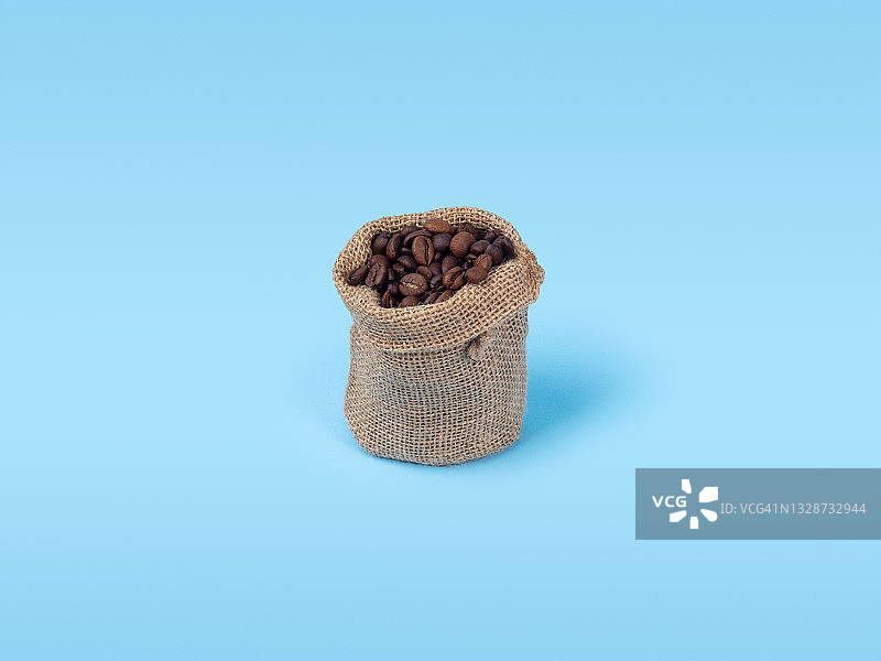 浅蓝色背景下的咖啡豆小麻袋图片素材