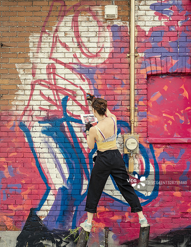 年轻女人在房子上画壁画图片素材