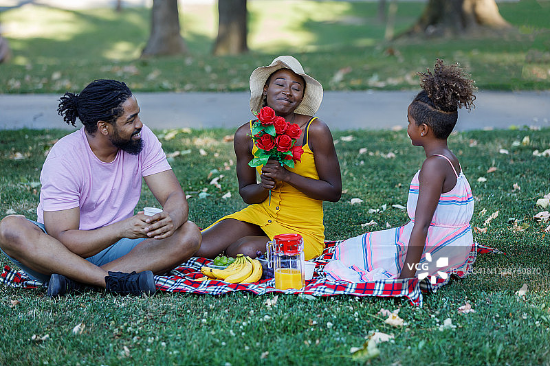快乐的非裔美国家庭享受户外水果鲜花野餐图片素材