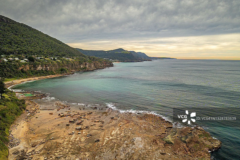 平坦的岩石海岸海岬、海浪、大海和山脉图片素材