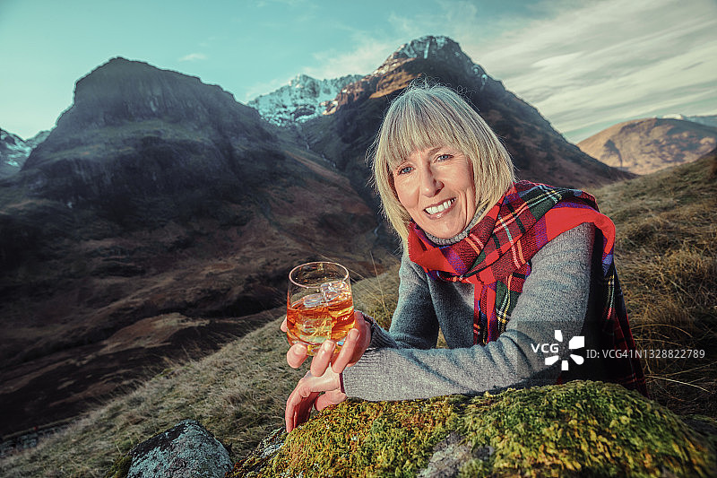 在苏格兰格兰科，手持威士忌酒杯的女人图片素材