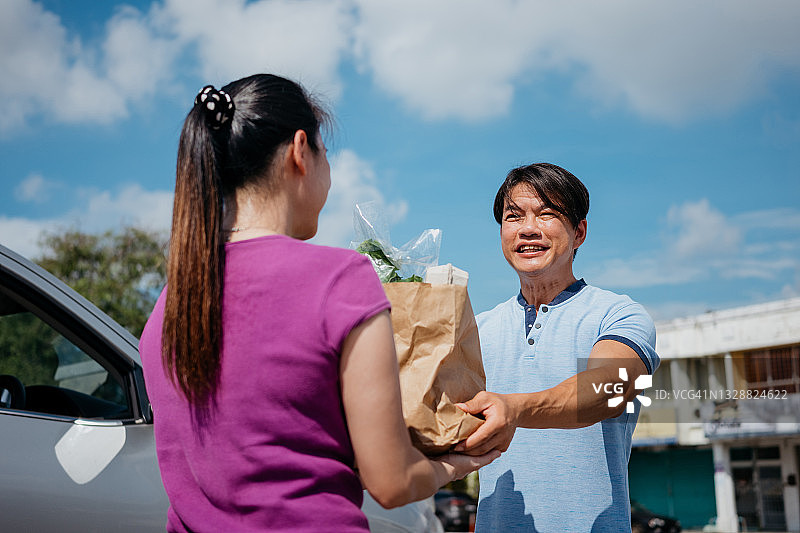 送货员将纸袋里的食品杂货送到顾客手中图片素材