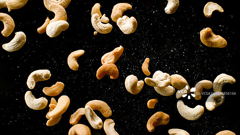 腰果掉落在黑色表面上图片素材