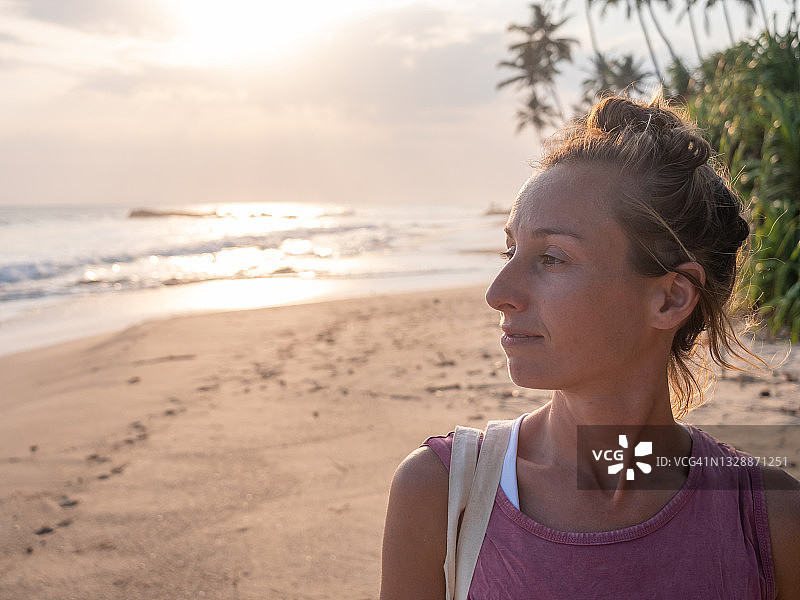 在当地海滩观看海岸线日落的女人图片素材