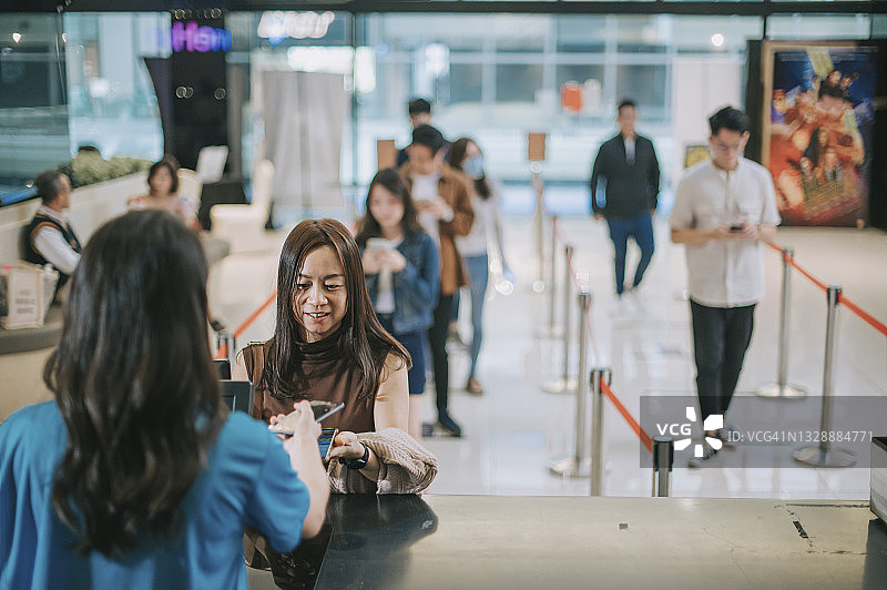 在电影院售票柜台前购买电影票和爆米花的亚洲华人女性观众图片素材