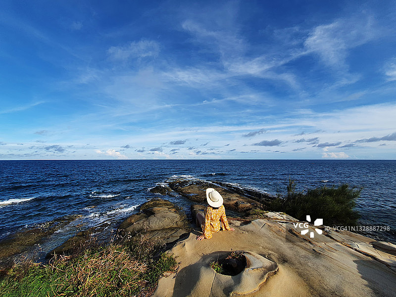 身穿黄裙的女人坐在婆罗洲古达沙巴悬崖边图片素材