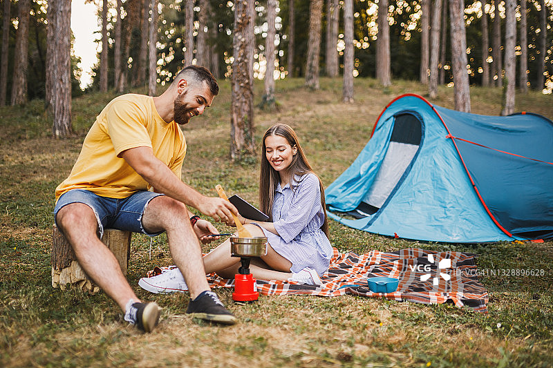 年轻情侣在森林里准备露营晚餐图片素材