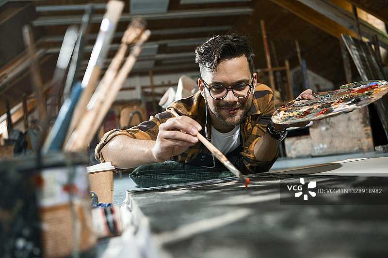 一位艺术家躺在地上在艺术工作室绘画的肖像图片素材