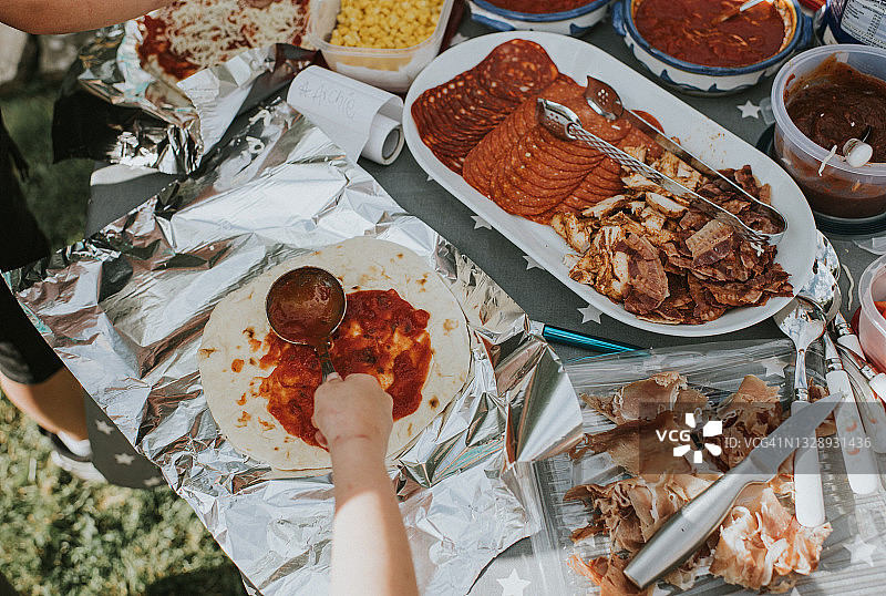 儿童自制披萨，将番茄酱涂在面团上图片素材