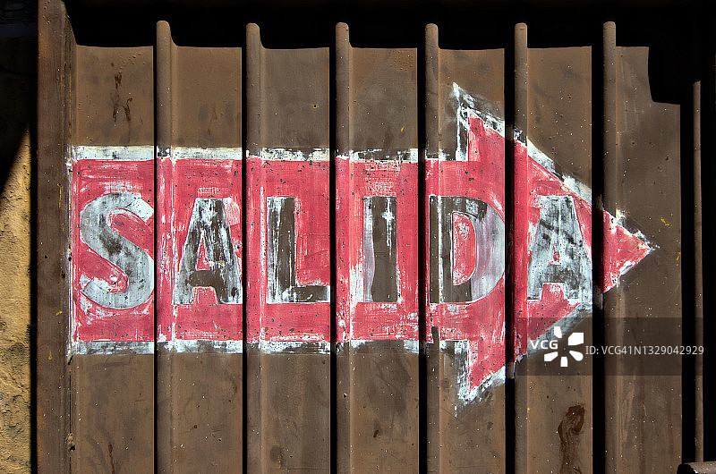 褪色的西班牙语“出口”标志棕色瓦楞铁栅栏门图片素材