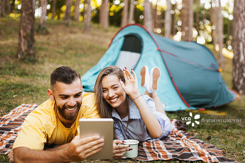 情侣在森林露营时进行视频通话图片素材