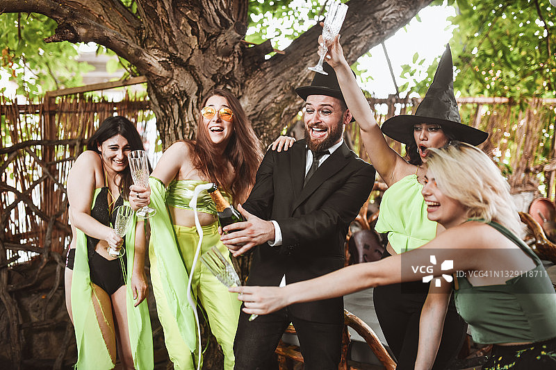 万圣节派对上向女性喷洒香槟的男人图片素材