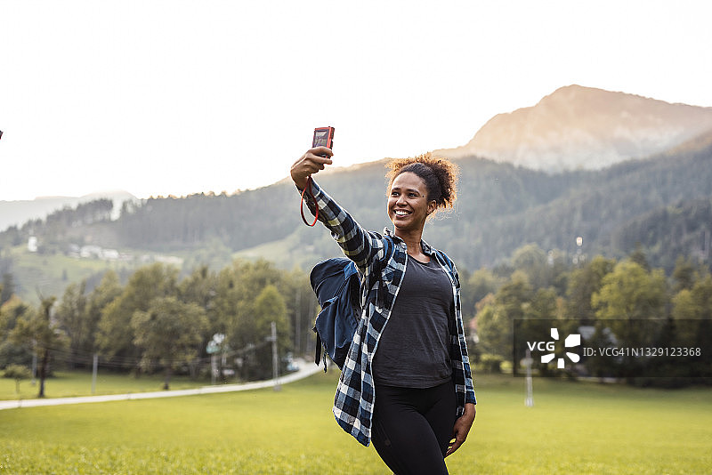 快乐的混血女徒步旅行者用相机自拍图片素材