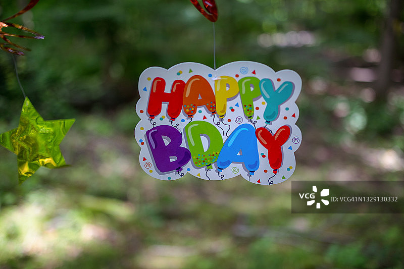 户外背景下手持气球造型的生日快乐纸牌图片素材