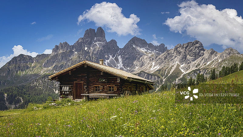 阿尔卑斯山宁静的山景：山间小屋、草地和蓝天图片素材