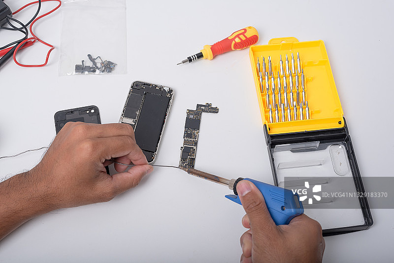 技术员用烙铁维修手机内部，集成电路，回收硬件技术概念图片素材