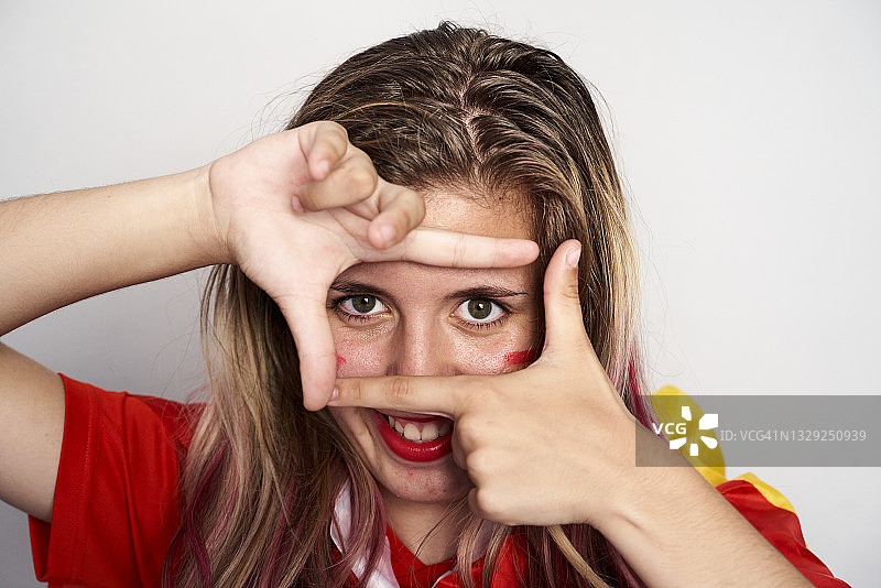 快乐的少女用手指和手做框架的肖像。图片素材