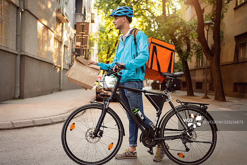 白人送货员骑自行车在城市里送餐图片素材